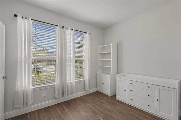 an empty room with wooden floor a fireplace and windows