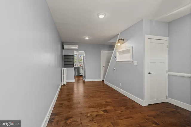 an empty room with wooden floor and a kitchen