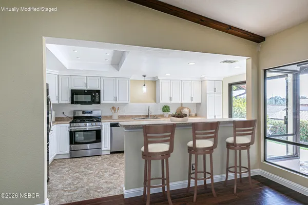 a kitchen with stainless steel appliances granite countertop a stove top oven a sink dishwasher a dining table and chairs with wooden floor