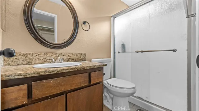 a bathroom with a granite countertop toilet a sink and a mirror