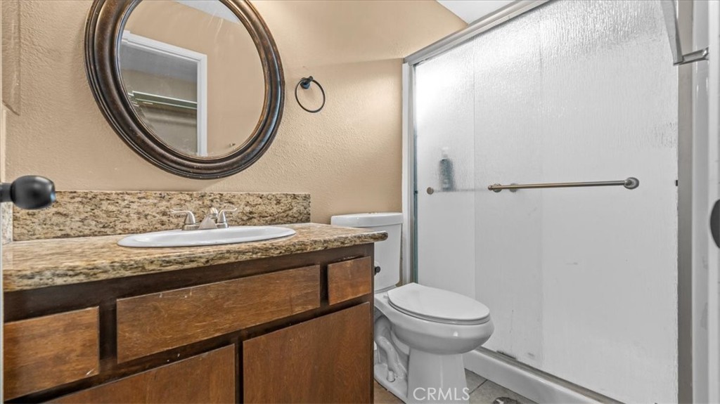 25607 Ash Road Barstow, CA 92311 - Photo 23 of 36 a bathroom with a granite countertop toilet a sink and a mirror