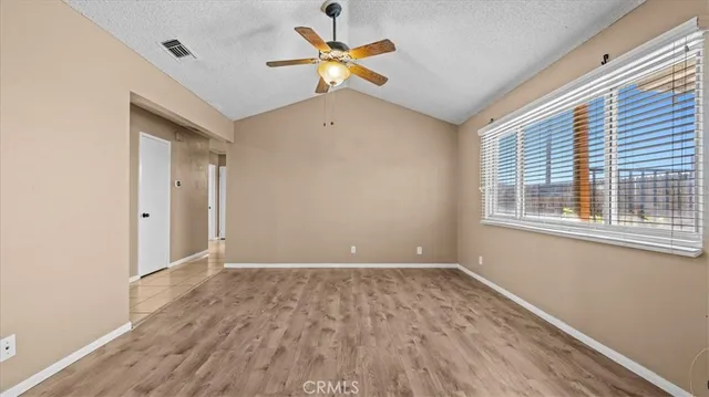 a view of an empty room with a window and wooden floor