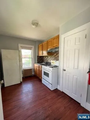 a kitchen with granite countertop wooden floors and white stainless steel appliances