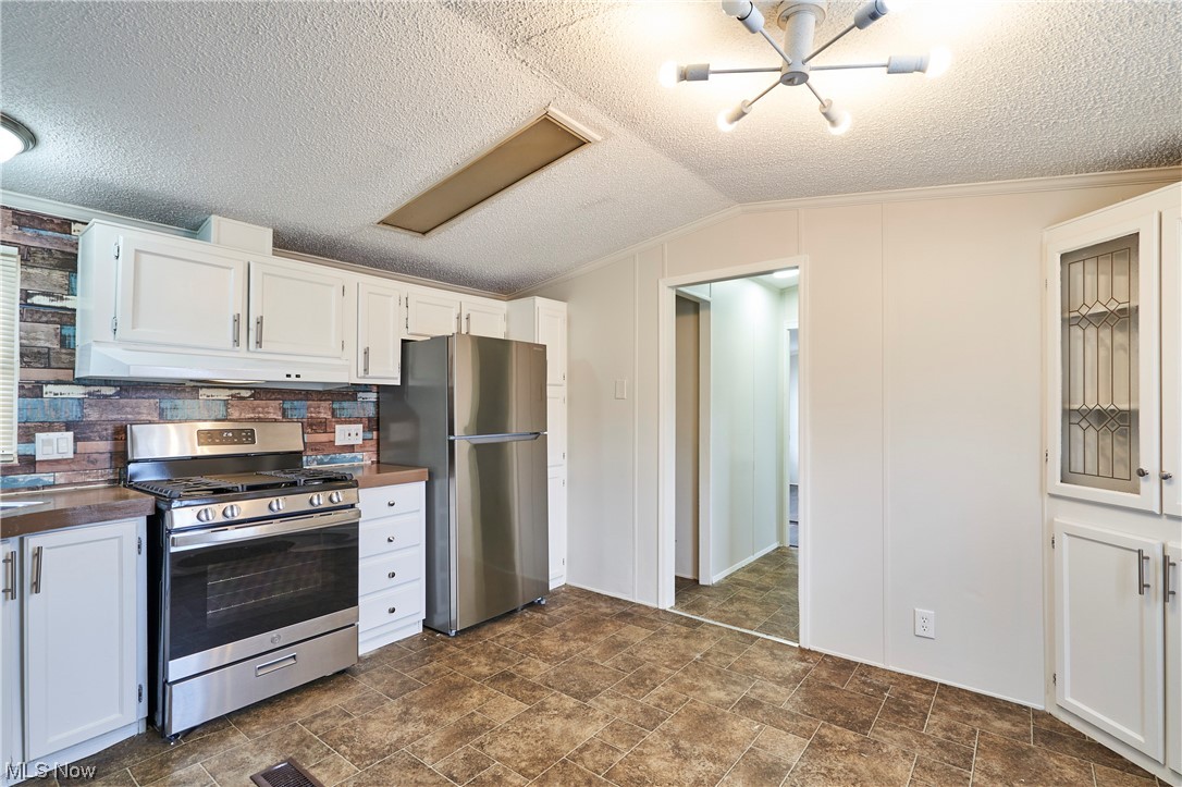 45 Eddie Road Madison, OH 44057 - Photo 7 of 26 Kitchen with white cabinets, appliances with stainless steel finishes, a textured ceiling, and a notable chandelier