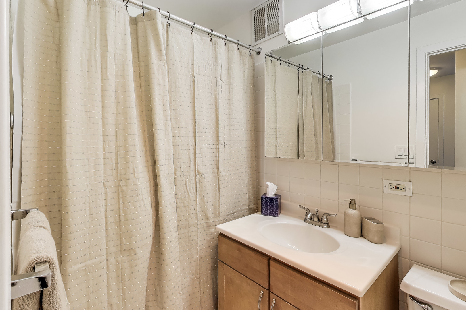 655 West Irving Park Road, Unit 606 Chicago, IL 60613 - Photo 19 of 29 a bathroom with a sink a mirror and a shower curtain