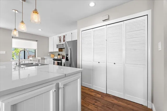 a kitchen with a refrigerator a sink and wooden floor