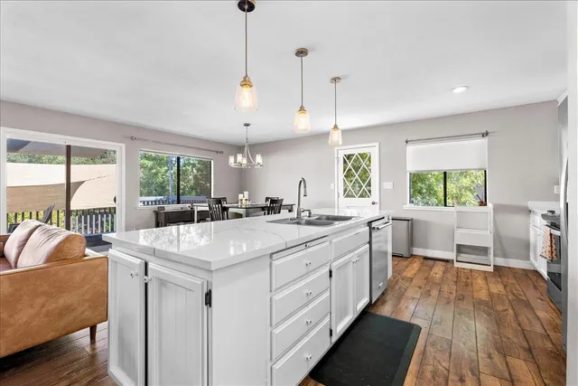 a large kitchen with kitchen island a large window a sink and living room view