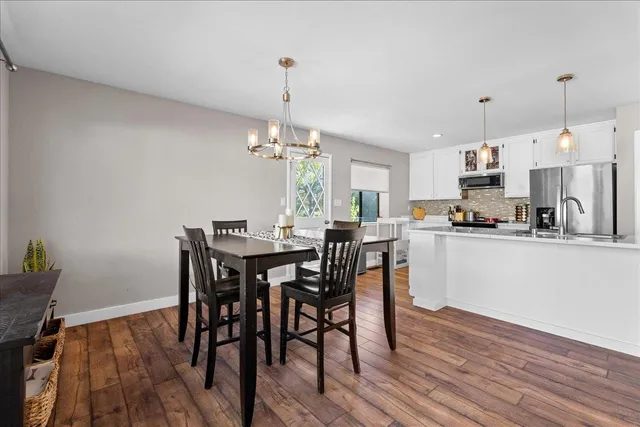 a view of kitchen with dining table chairs wooden floor and appliances
