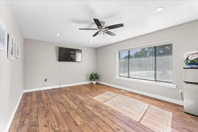 a view of an empty room with wooden floor and a window