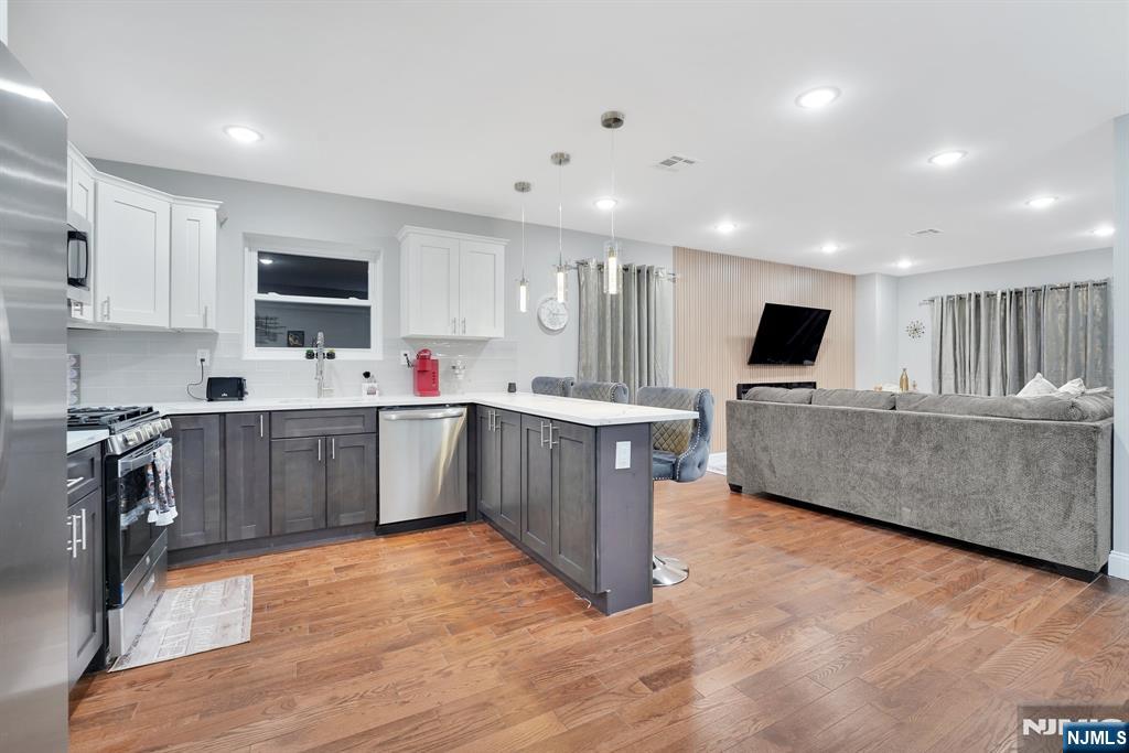225 South 9th Street Newark, NJ 07103 - Photo 20 of 35 a large kitchen with stainless steel appliances granite countertop a stove top oven a sink dishwasher and a microwave with wooden floor