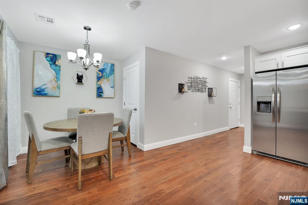 225 South 9th Street Newark, NJ 07103 - Photo 22 of 35 a dining room with wooden floor a chandelier a wooden table and chairs