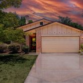 a view of a white house with a small yard and large tree