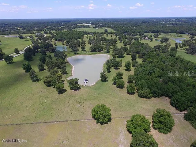 an aerial view of a houses with a yard and lake view