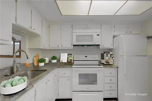 a kitchen with refrigerator a stove a sink and white cabinets