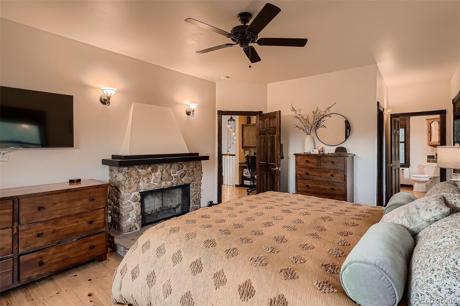 2169 Dory Hill Road Black Hawk, CO 80422 - Photo 16 of 46 a spacious bedroom with a bed a fireplace and a flat screen tv