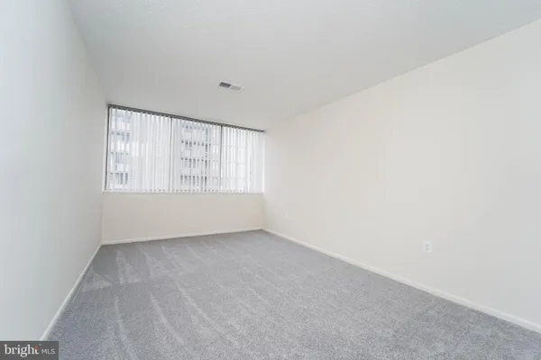 a view of an empty room with wooden floor and closet