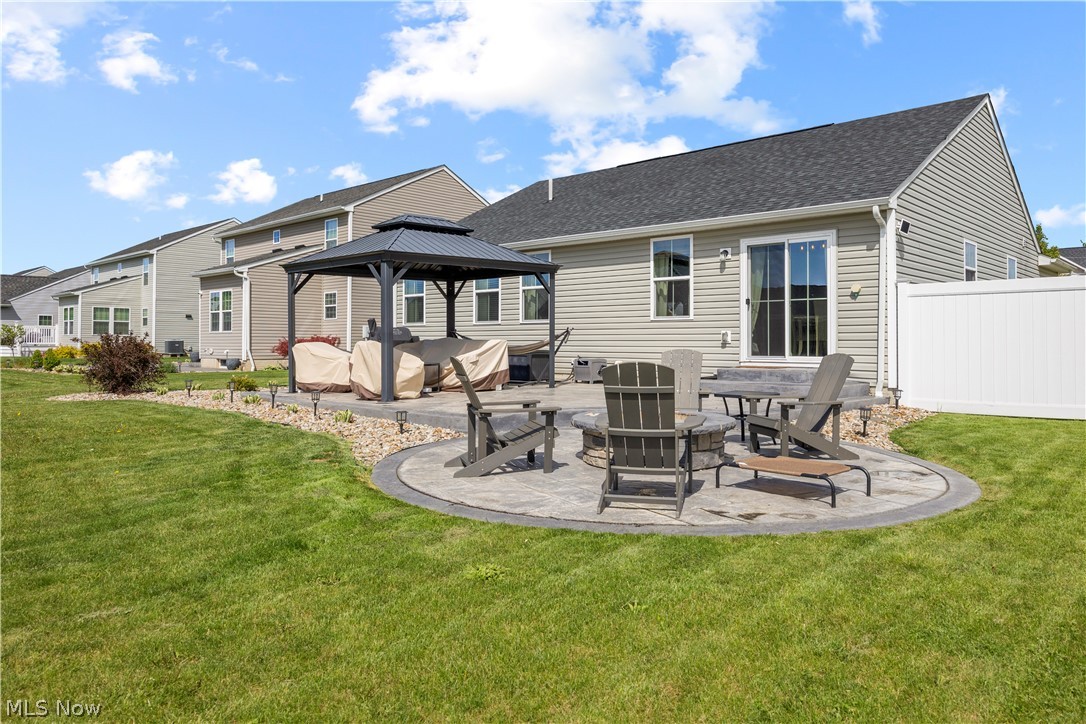 2161 Fowl Road Elyria, OH 44035 - Photo 37 of 46 Expansive backyard featuring a circular paver patio with a built-in fire pit, a dedicated covered gazebo area, and a sliding glass door for interior access