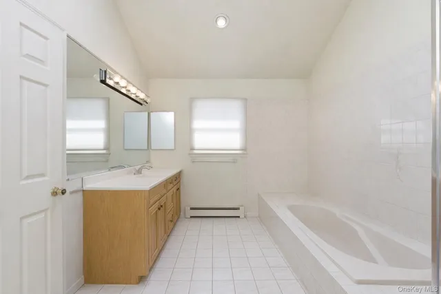 a bathroom with a tub sink and mirror