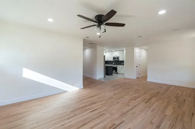 a view of an empty room with a ceiling fan and wooden floor