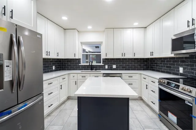 a kitchen with stainless steel appliances granite countertop a stove a sink and a refrigerator