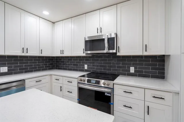 a kitchen with granite countertop white cabinets and stainless steel appliances