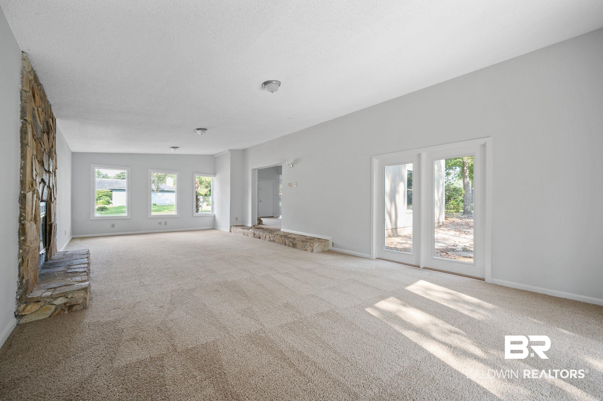 3701 Vista Ridge Drive Mobile, AL 36693 - Photo 22 of 33 Unfurnished living room with vaulted ceiling, a stone fireplace, and carpet flooring