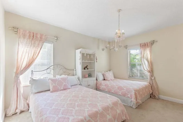 a bedroom with two large bed and a chandelier
