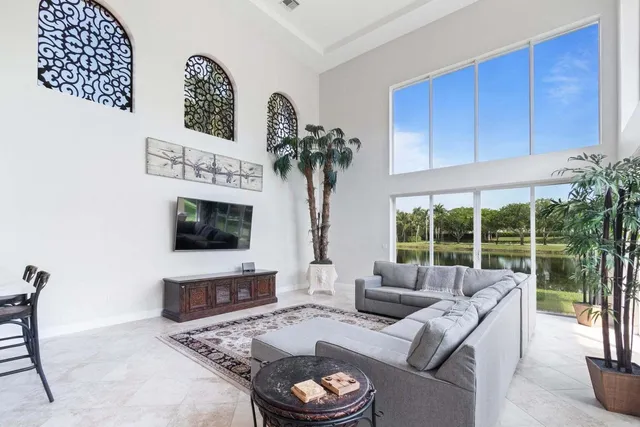 a living room with furniture a flat screen tv and a floor to ceiling window