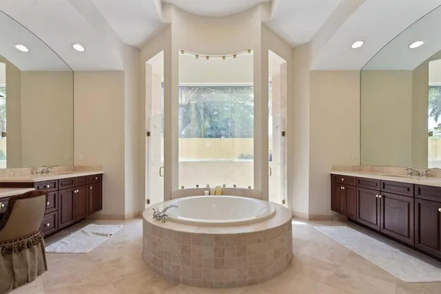 a spacious bathroom with a tub a sink and mirror