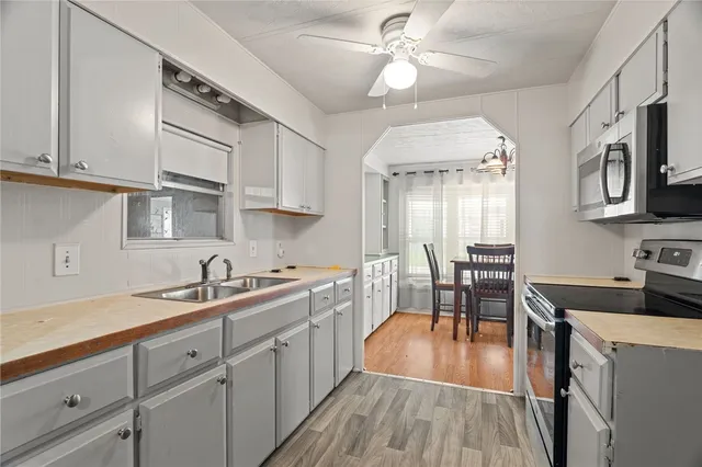 a kitchen with stainless steel appliances a stove a sink dishwasher a dining table and chairs with wooden floor