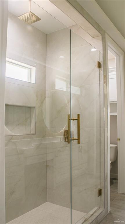 900 Azalea Street Mission, TX 78573 - Photo 11 of 12 Glass-enclosed shower with gold-tone hardware, a rain showerhead, and light-toned, veined tile surrounds