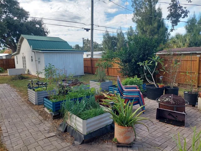 a view of a backyard with potted plants and large tree