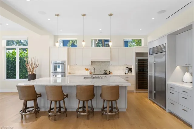 a kitchen with stainless steel appliances kitchen island granite countertop a table chairs sink and cabinets