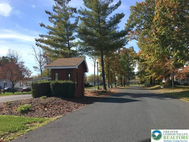 a view of a white house with a big yard and large trees