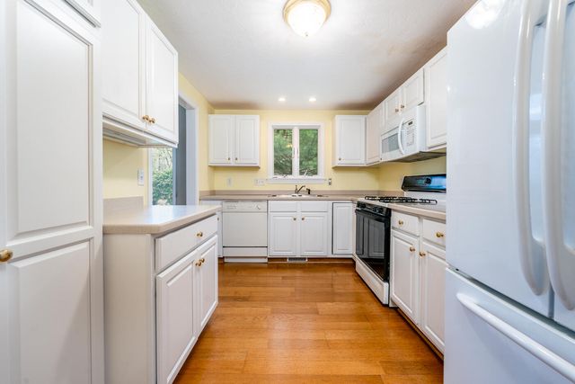 a kitchen with white cabinets appliances and a window