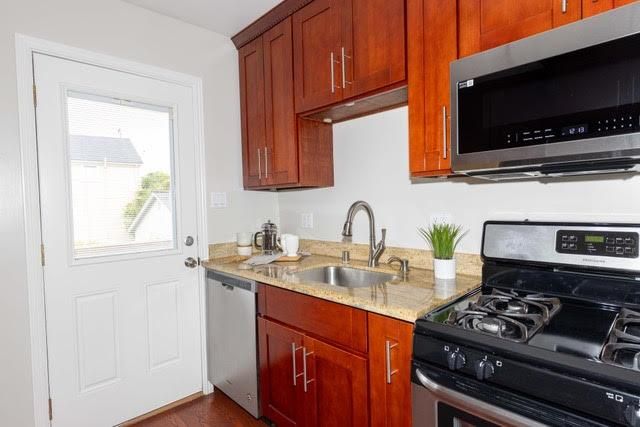 a kitchen with stainless steel appliances granite countertop a sink stove and microwave