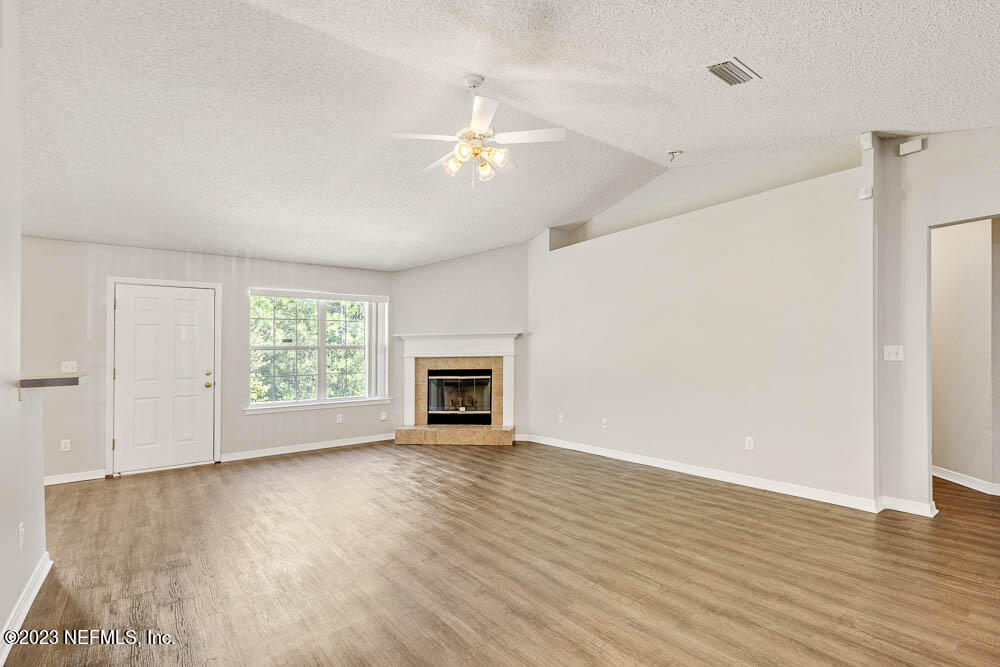 1399 Guardian Drive Jacksonville, FL 32221 - Photo 8 of 29 an empty room with wooden floor chandelier fan and windows