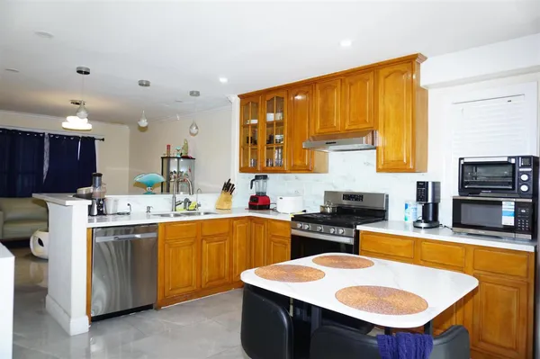 a kitchen with stainless steel appliances a sink a stove a refrigerator cabinets and dining table