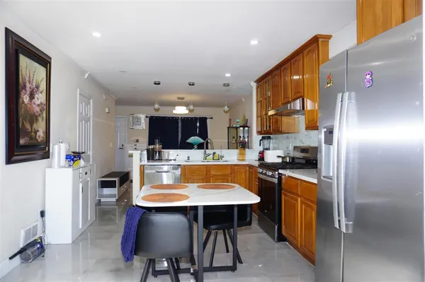 a kitchen with stainless steel appliances a dining table chairs refrigerator and sink