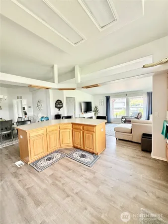a large white open kitchen with a white countertops a couch and a dining table view