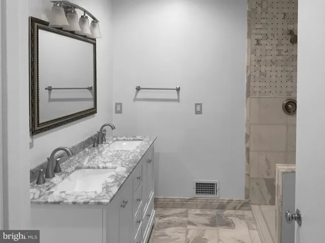 a bathroom with a granite countertop sink a mirror and shower