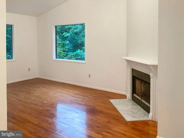 an empty room with wooden floor cabinet and windows