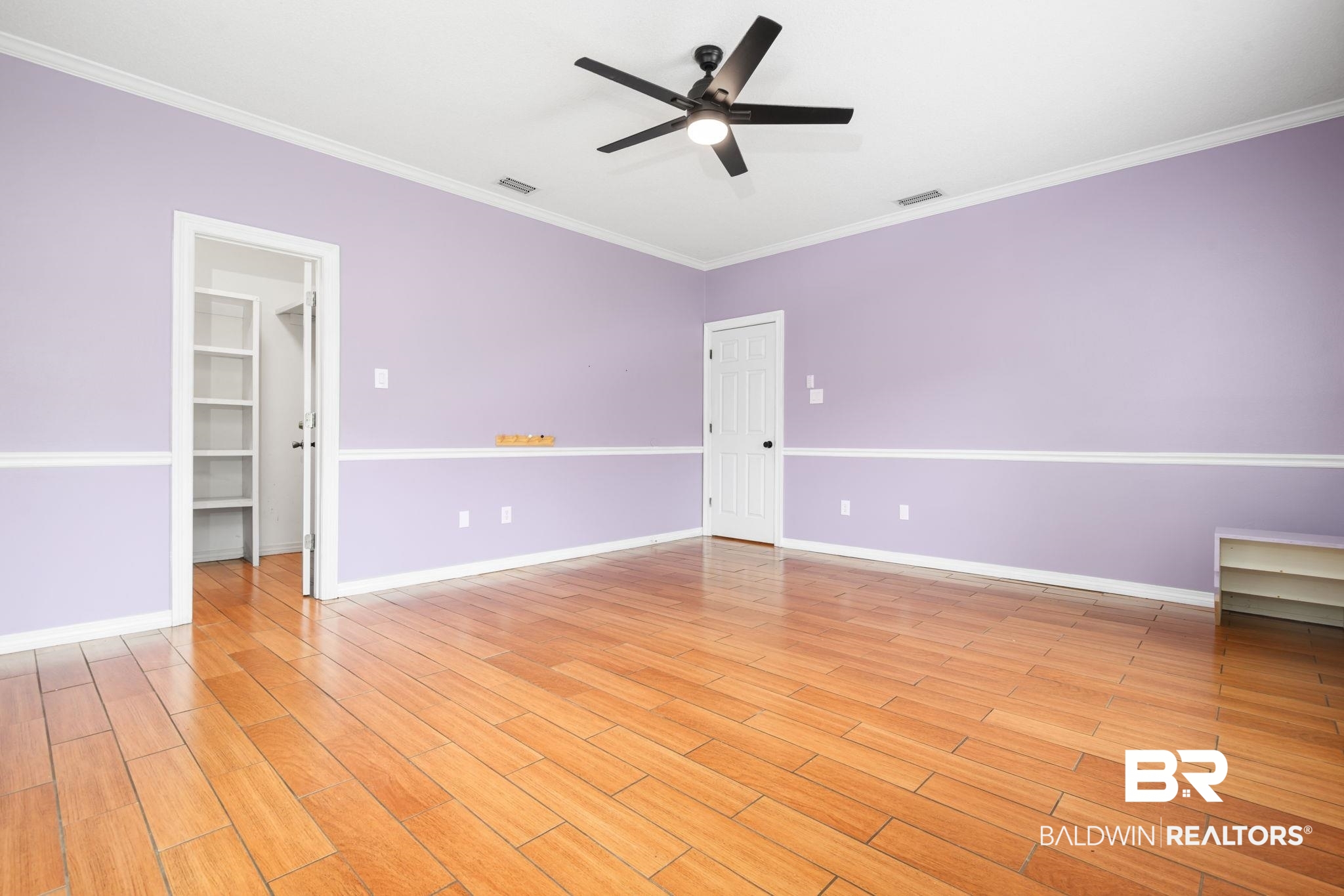 7540 2 Mile Road Irvington, AL 36544 - Photo 54 of 82 Spacious interior room featuring wood-finish flooring, a ceiling fan with integrated lighting, and white baseboards and crown molding