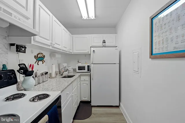 a kitchen with granite countertop white cabinets and white appliances