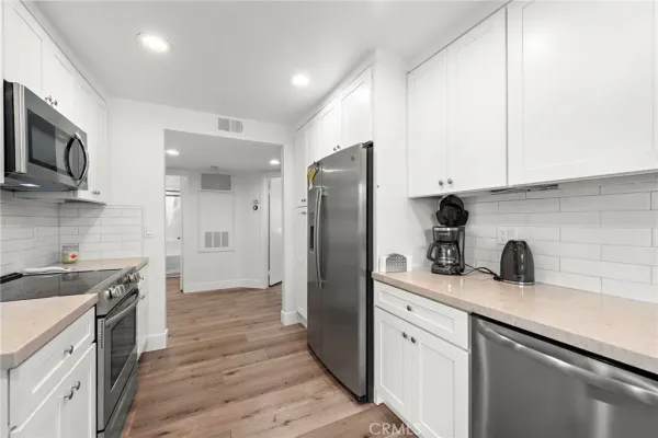 a kitchen with stainless steel appliances a sink stove refrigerator and cabinets