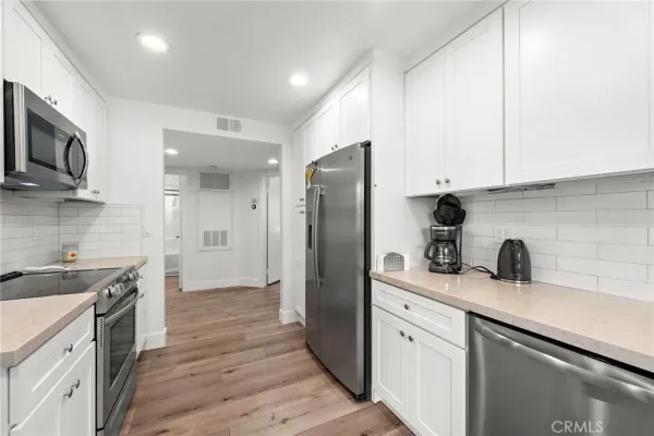 a kitchen with stainless steel appliances a sink stove refrigerator and cabinets