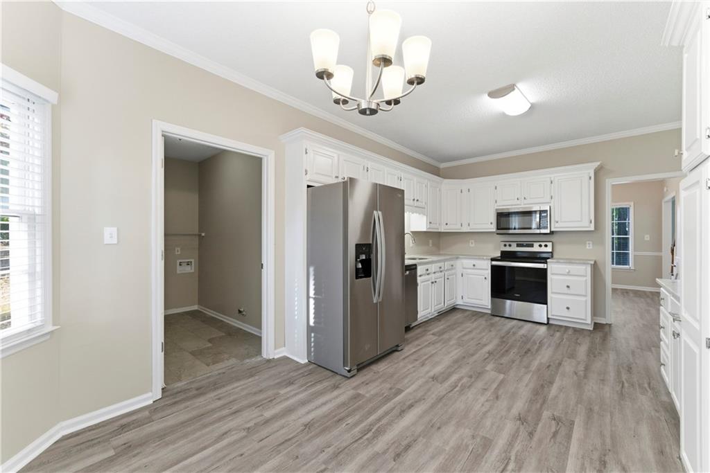1043 Sterling Ridge Chase Northeast Marietta, GA 30062 - Photo 3 of 14 a kitchen with granite countertop a refrigerator oven a sink dishwasher and white cabinets with wooden floor