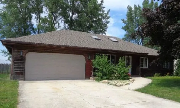 a view of a house with a yard plants and large tree