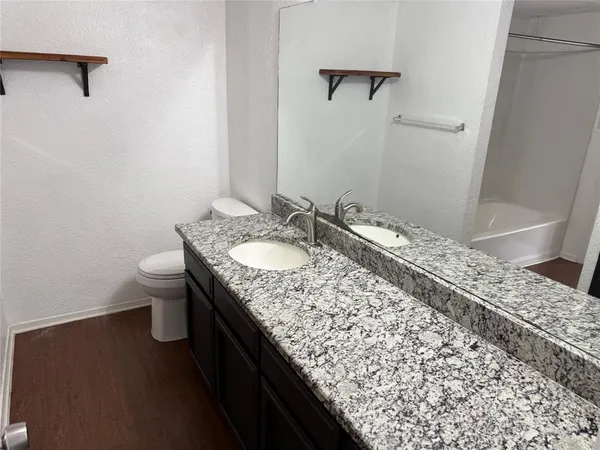 a bathroom with a granite countertop sink and a toilet
