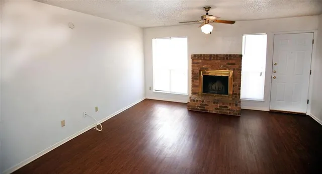 an empty room with wooden floor fireplace and fan